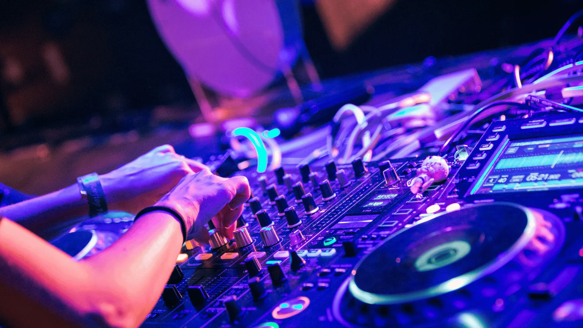 DJ skruer på mixeren i lilla og blåt scenelys